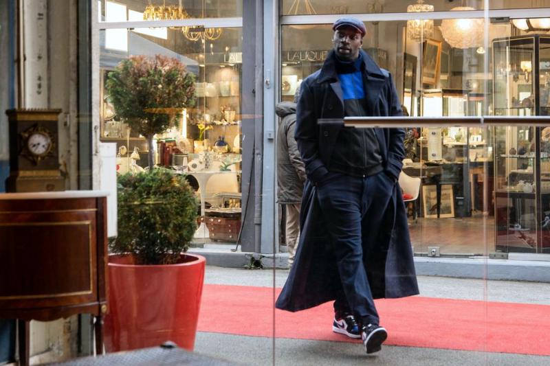 Assane enters Benjamin's shop at the Marché Biron