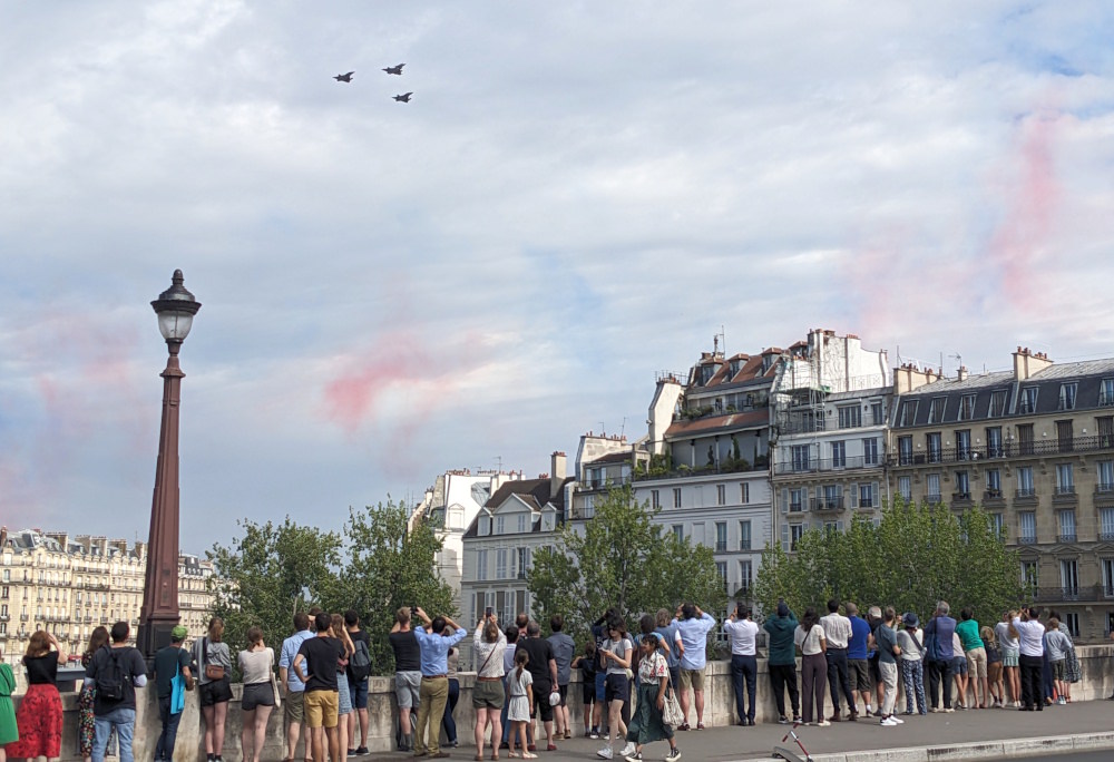 Parisians watch the Bastille Day flyover from the Pont de la Tournelle