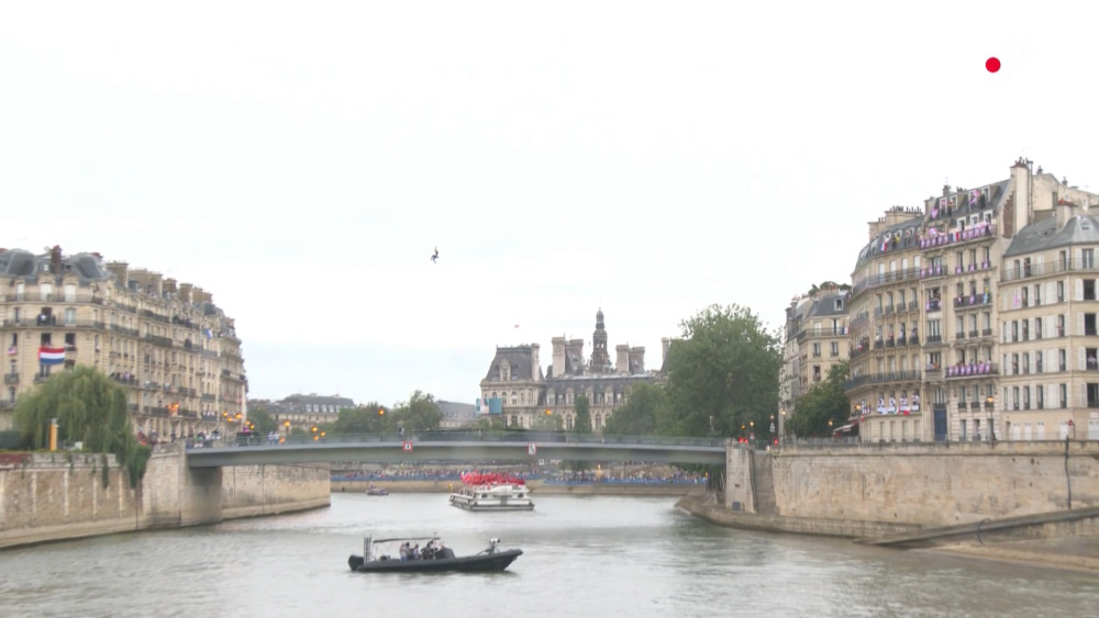 The masked figure ziplines across the Seine