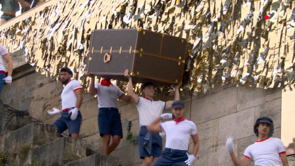 Louis Vuitton trunk being carried down to the river