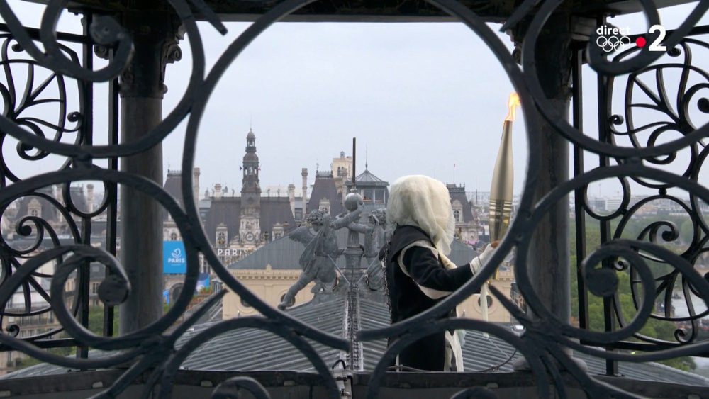 The hooded torch bearer enters the Châtelet Théâtre