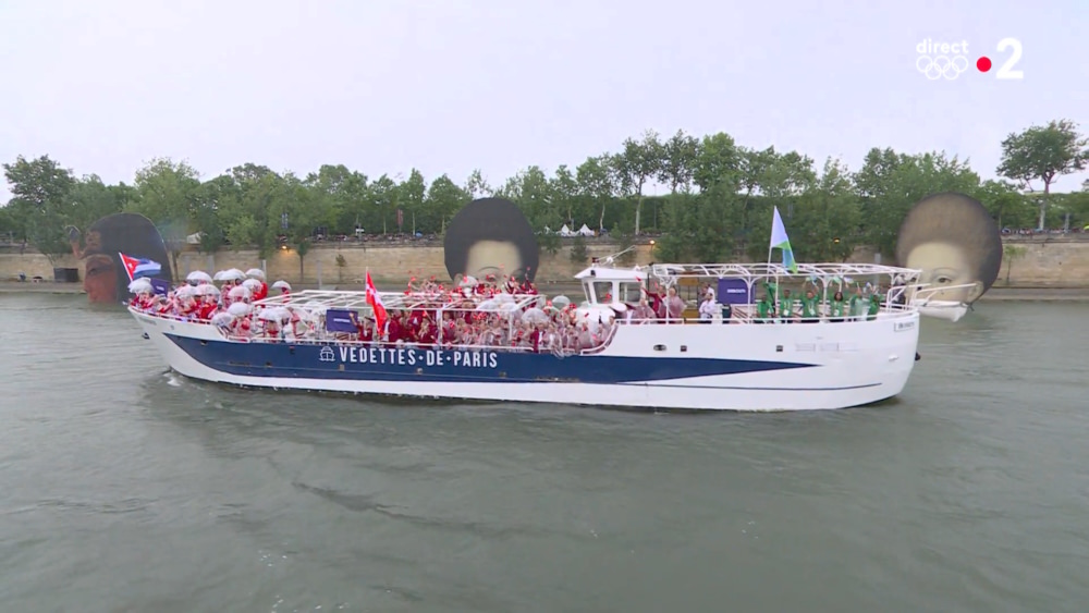 Athletes on boats going down the Seine past artworks from the Louvre